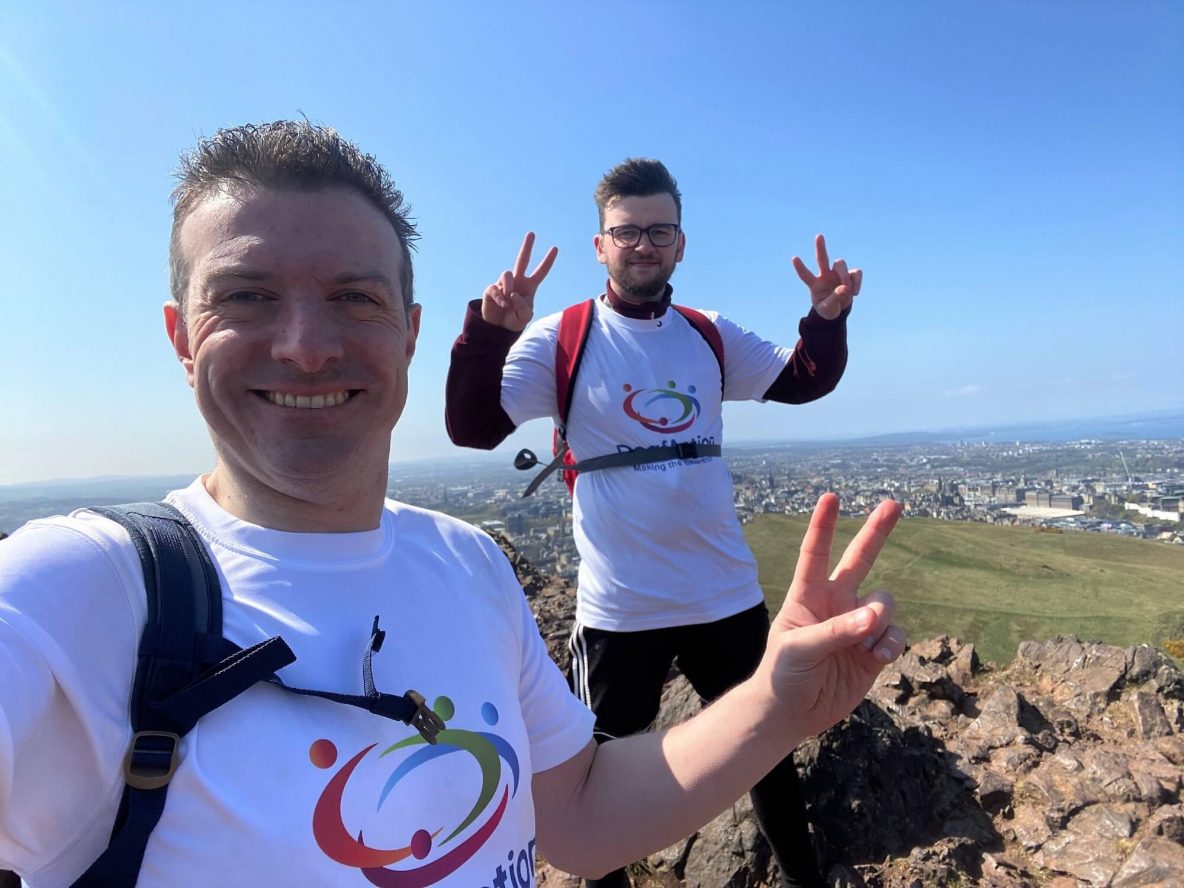 Two men wearing Deaf Action t-shirts and smiling