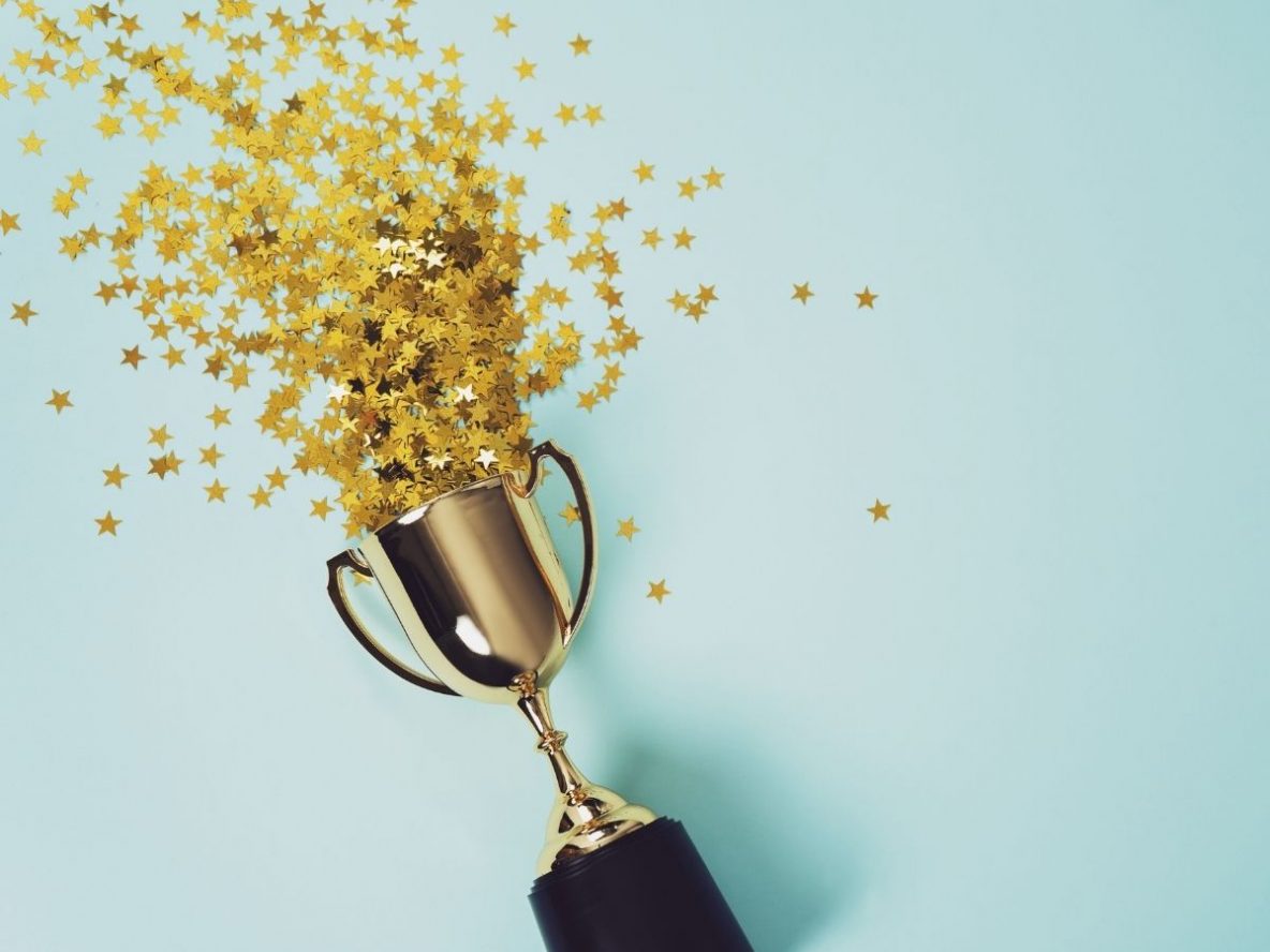Gold trophy on blue background, surrounded by gold stars