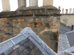 Chimney on top of roof with damaged stonework